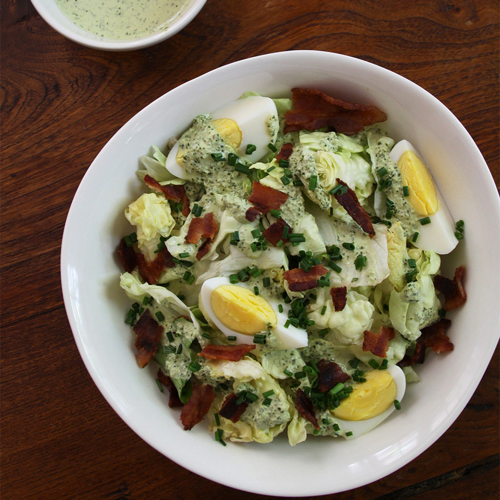 Butter lettuce salad with bacon, hard-boiled egg and chives under creamy green basil dressing.