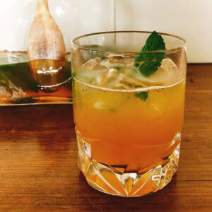 Whiskey smash over ice in a cut crystal rocks glass with a fresh mint sprig.
