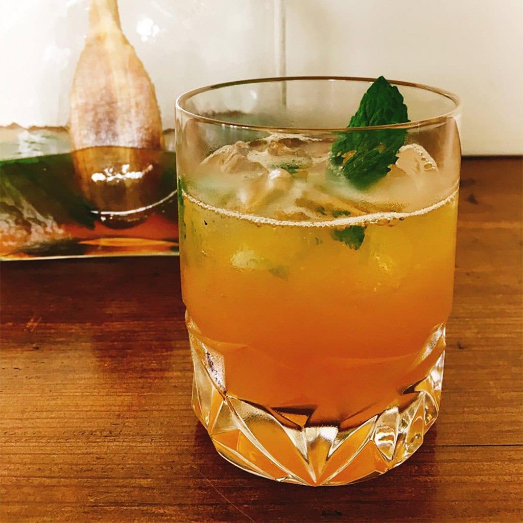 Whiskey smash over ice in a cut crystal rocks glass with a fresh mint sprig.