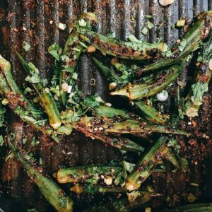Blistered okra with Sichuan peppercorns, chile flakes and fresh cilantro across a cast iron grill pan.