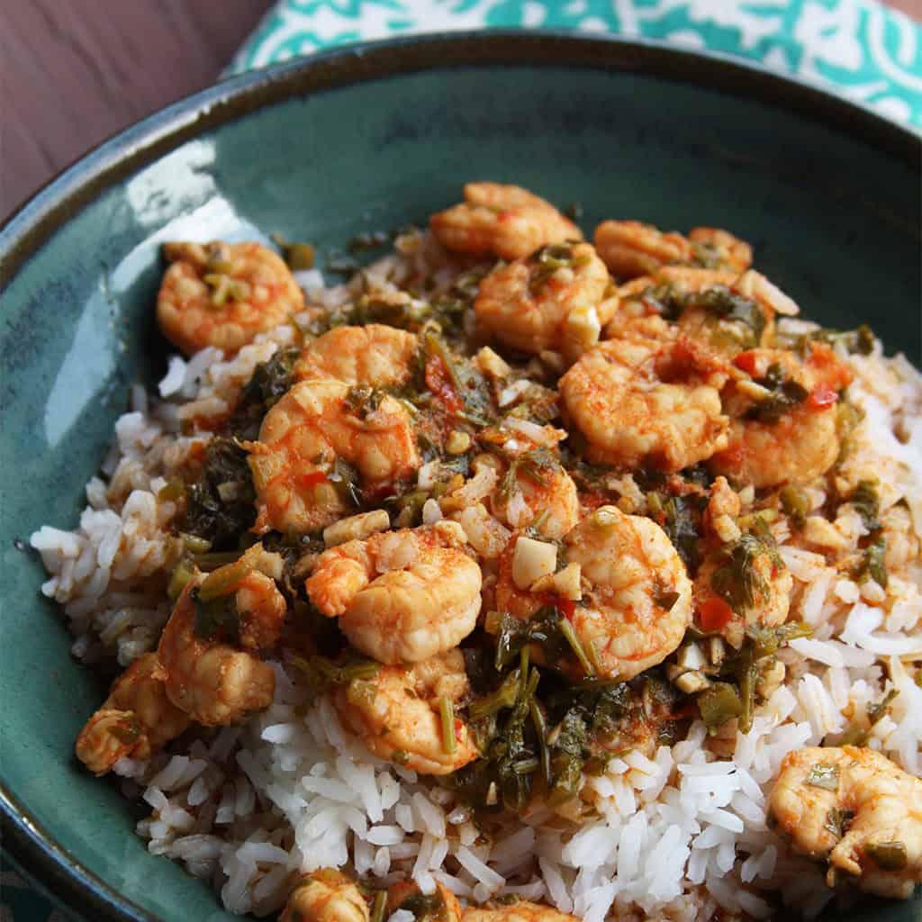 Cilantro lime shrimp in a herby pan sauce served over white rice in a teal bowl.