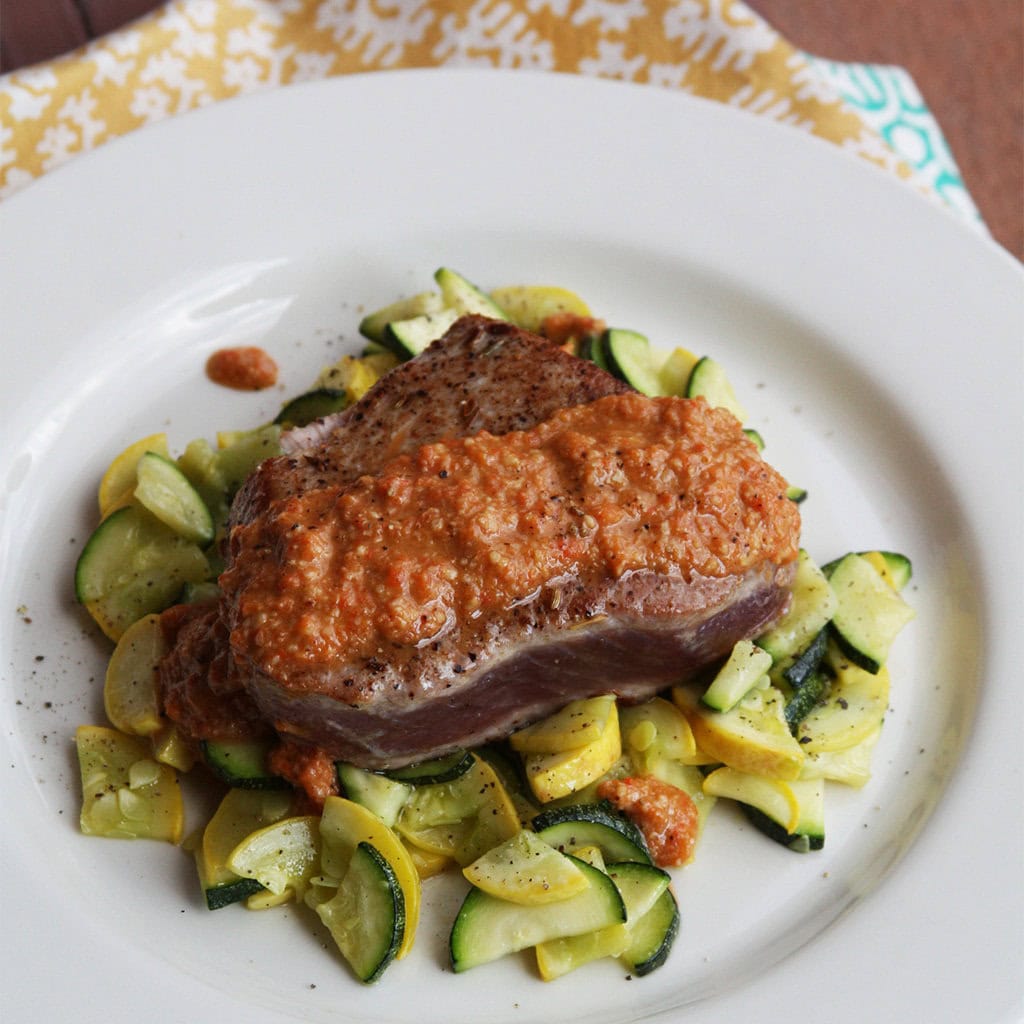 Seared tuna steak topped with Turkish red pepper walnut puree over sauteed summer squash.