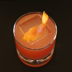 Overhead view of The Nameless cocktail with a curled orange peel resting on the ice cube.