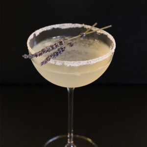 Two Meadows Martini in a sugar-rimmed coupe garnished with two dried lavender sprigs.