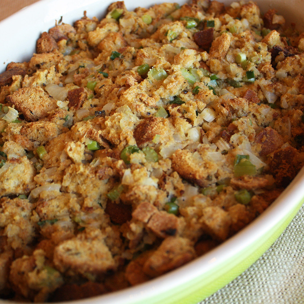 Focaccia herb stuffing with Italian sausage, celery and poblano peppers baked in a white dish.