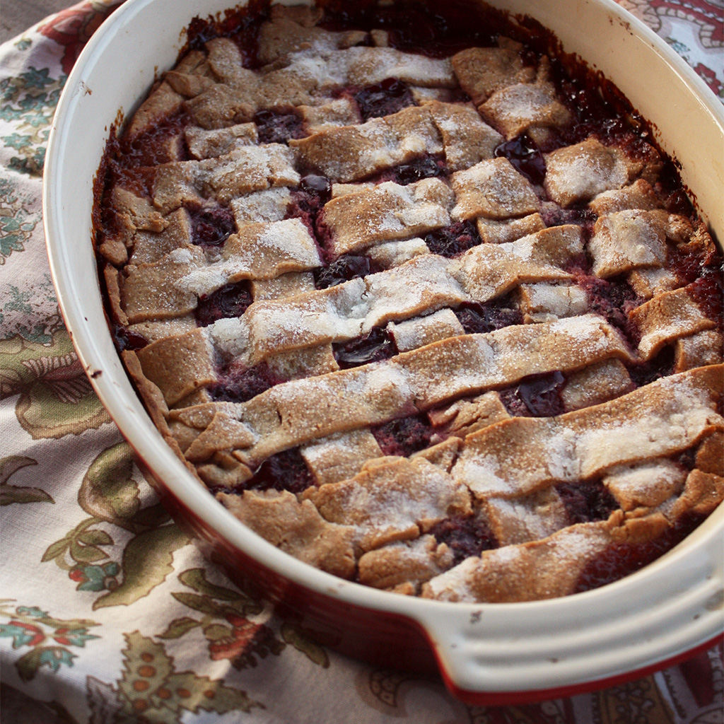 Texas dewberry cobbler with a lattice crust dusted in sugar, bubbling purple fruit beneath.