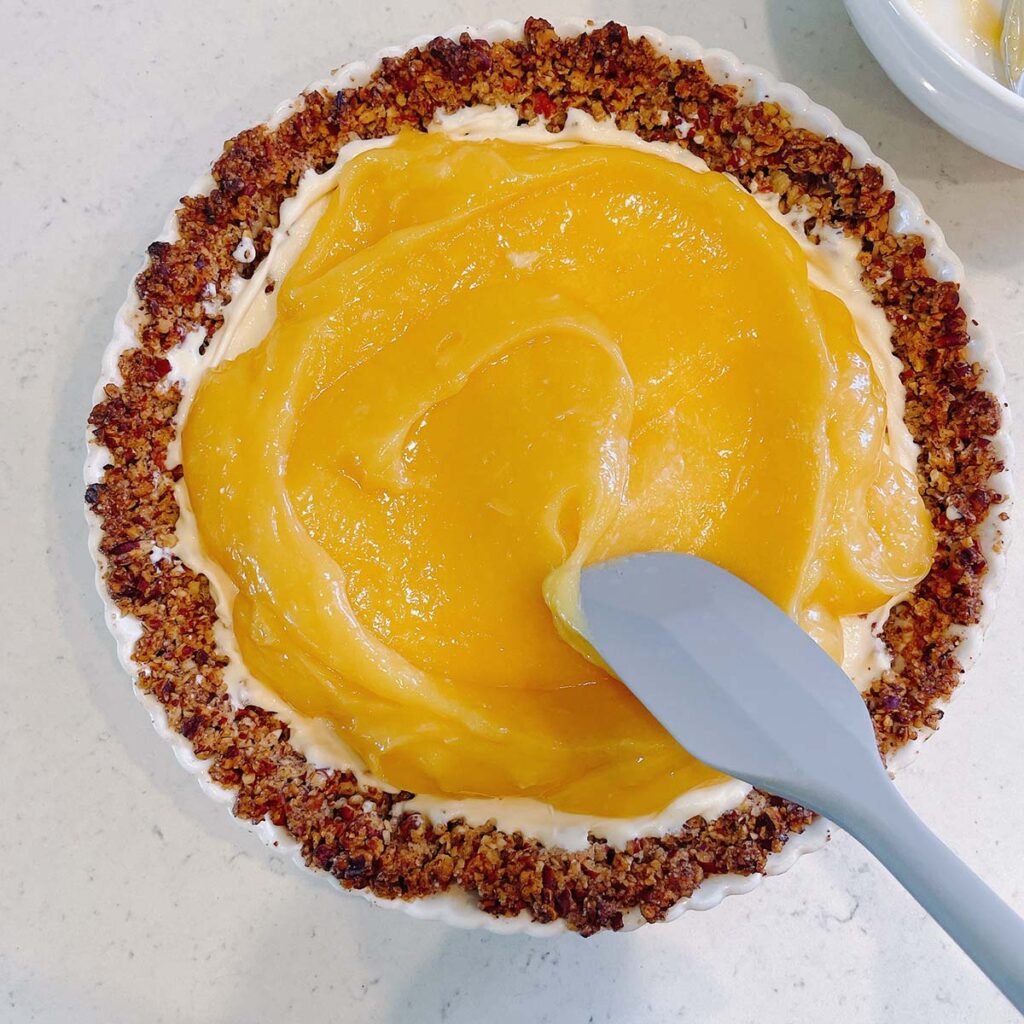 Lemon curd spread into a pie with toasted pecan crust.